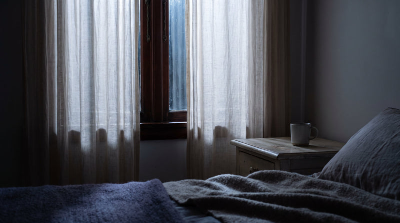 Moonlight filtering through sheer linen curtains at a bedroom window at night